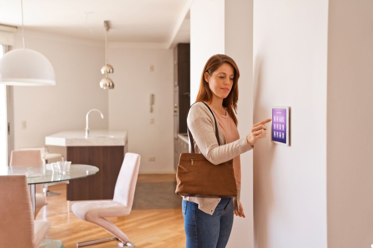 A woman stands in front of a wall-mounted touchscreen, interacting with the display in a modern environment. 