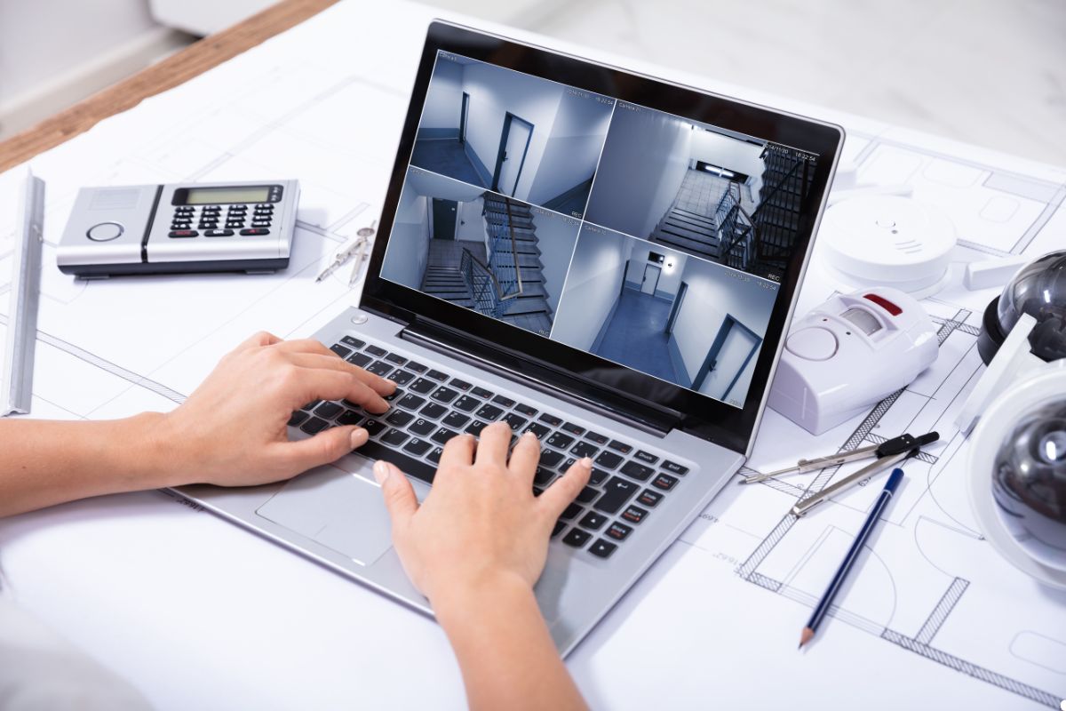 A person typing on a laptop with a camera, focused on their work in a well-lit environment.